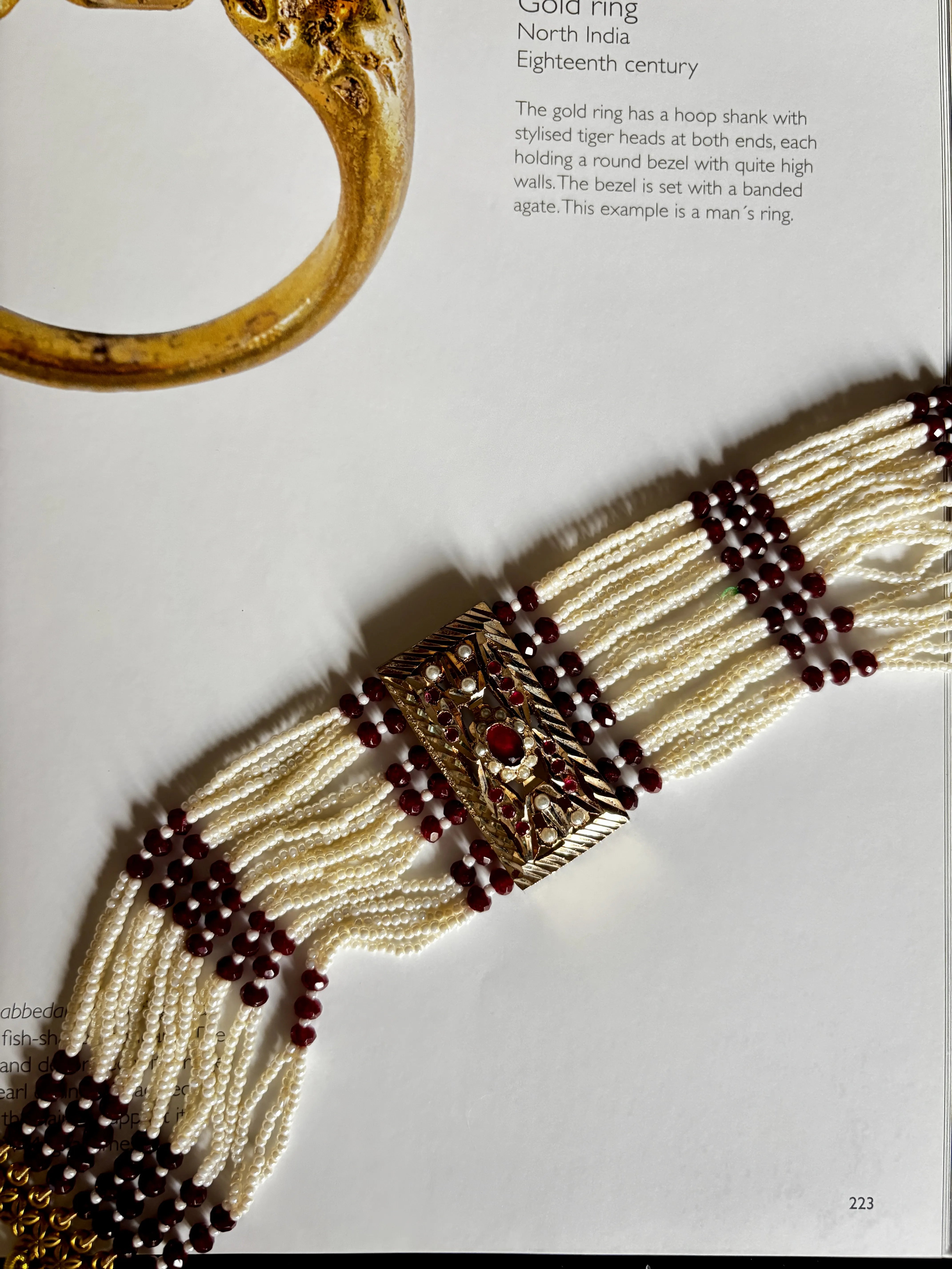 Close-up of a beaded bracelet with gold and red accents on a white background