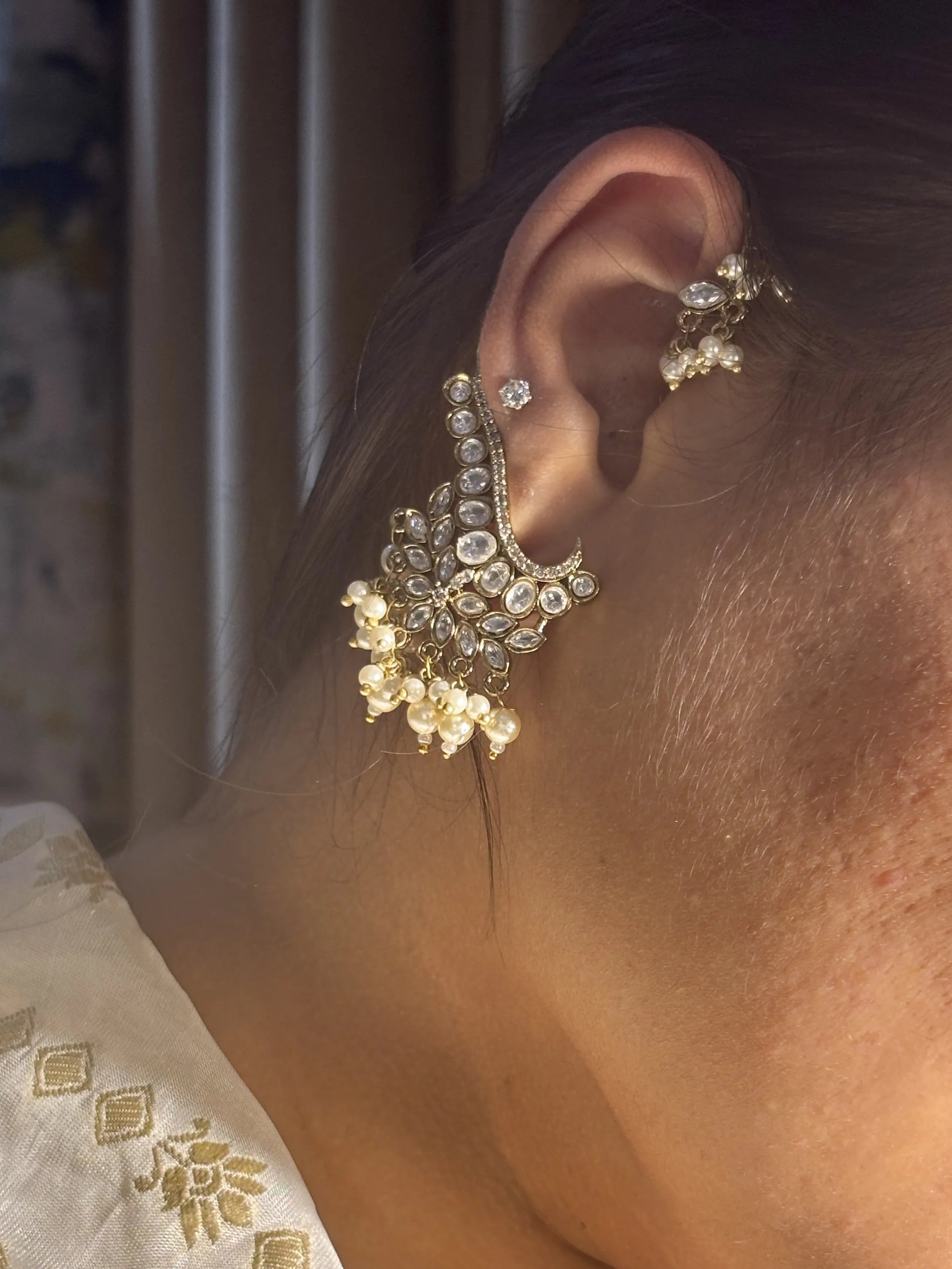 Close-up of a person wearing a decorative earring with a blurred background
