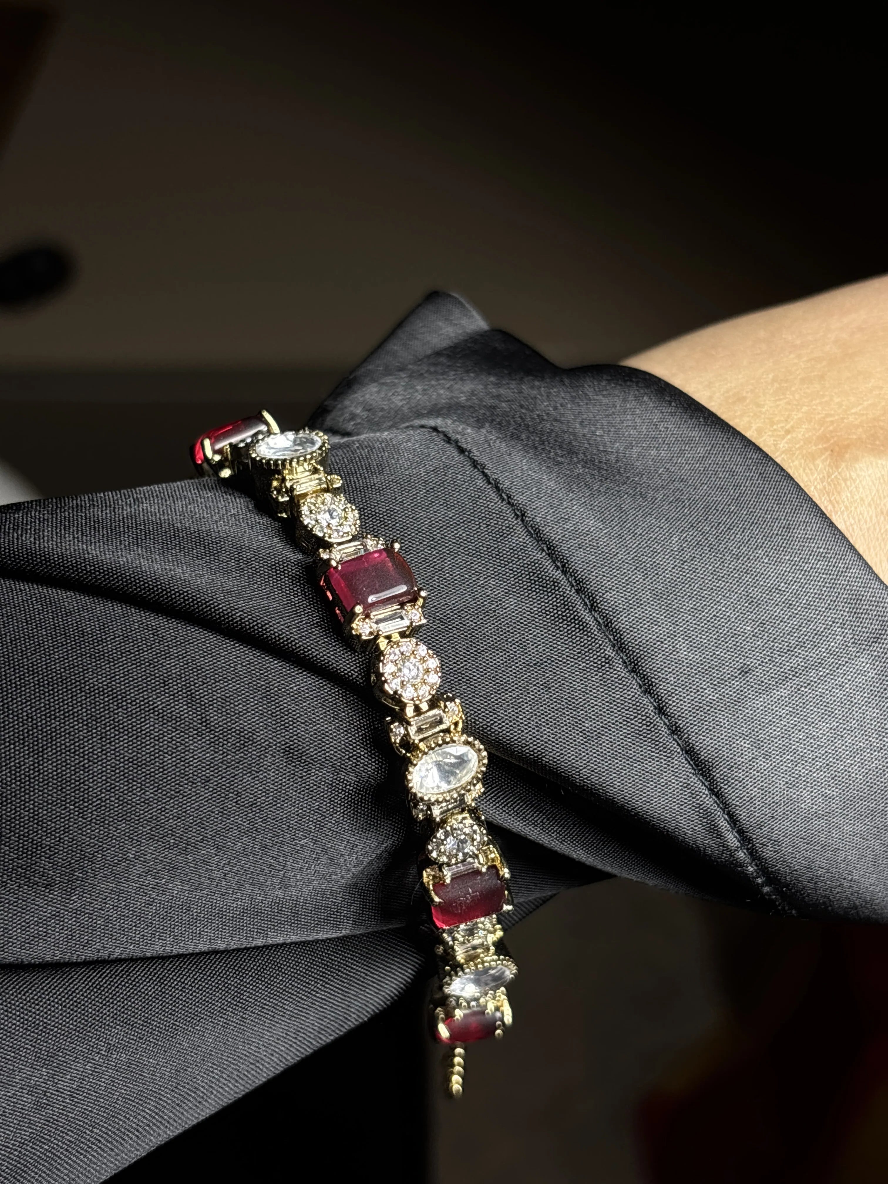 Bracelet with red gemstones and gold accents on a dark fabric background