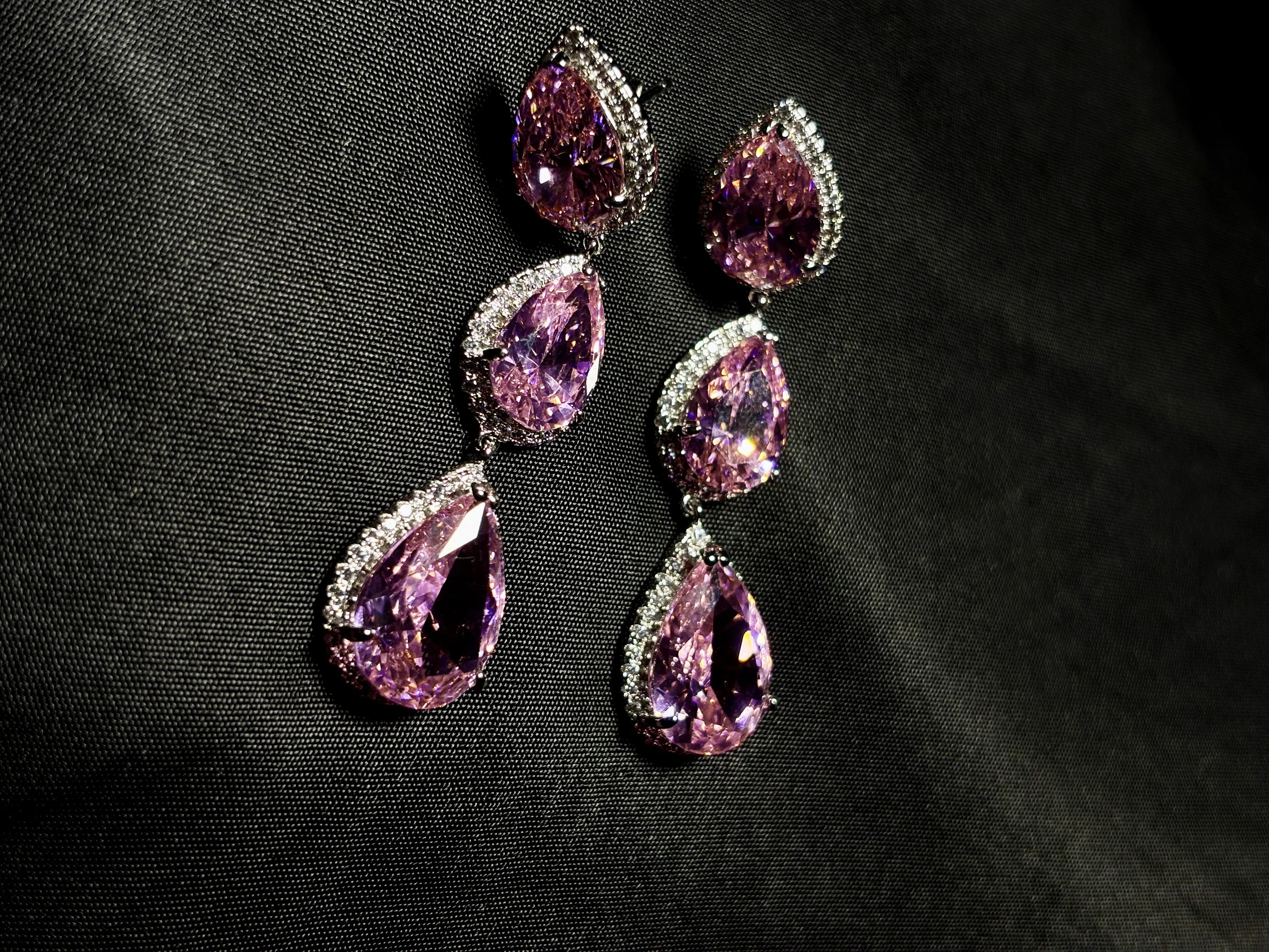 Set of purple teardrop-shaped gemstones with silver accents on a black background