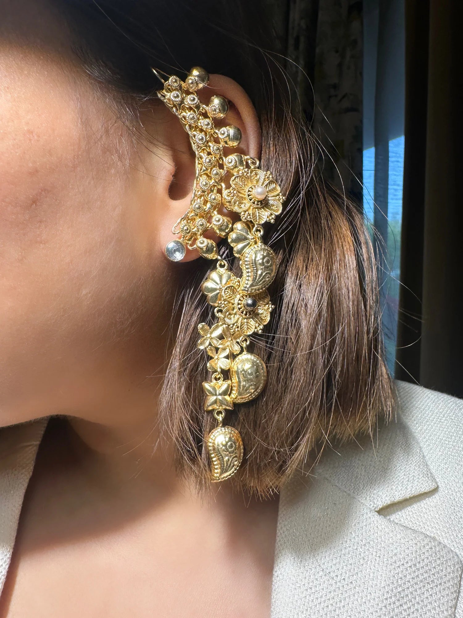 Close-up of a person wearing a gold earring with a blurred background