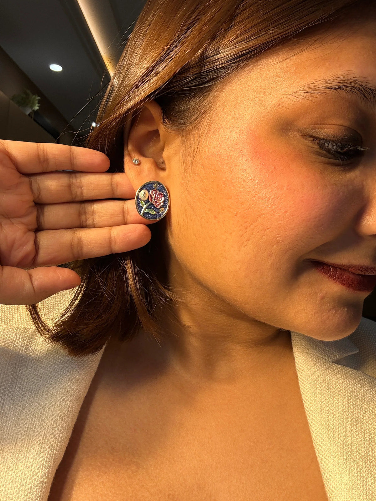 Close-up of a person wearing a floral earring with a blurred background